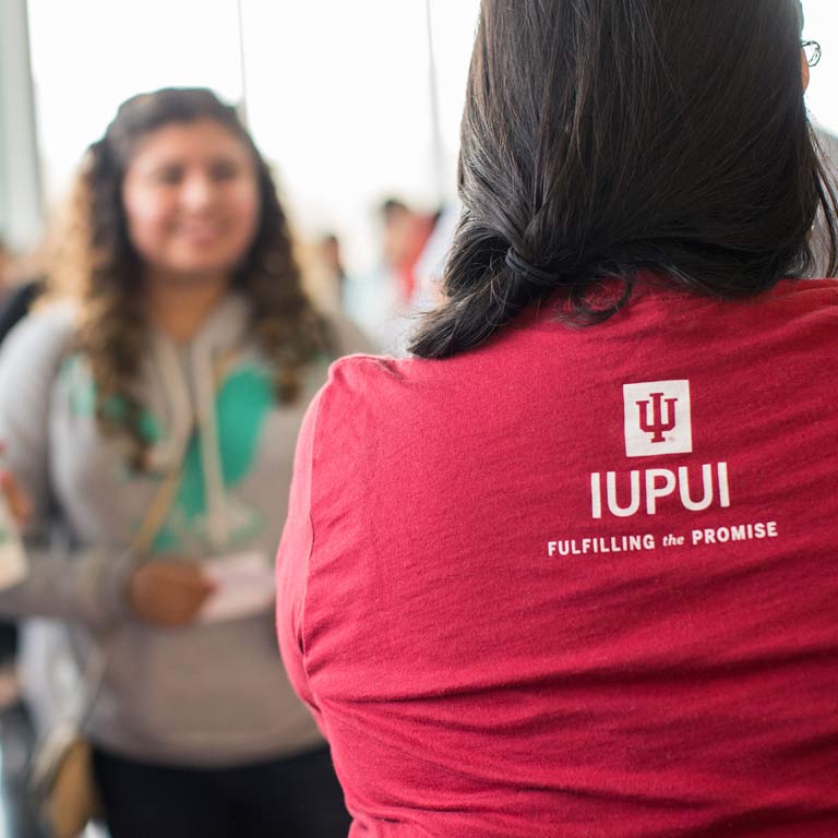 A person wearing a red IUPUI shirt faces away from the camera.