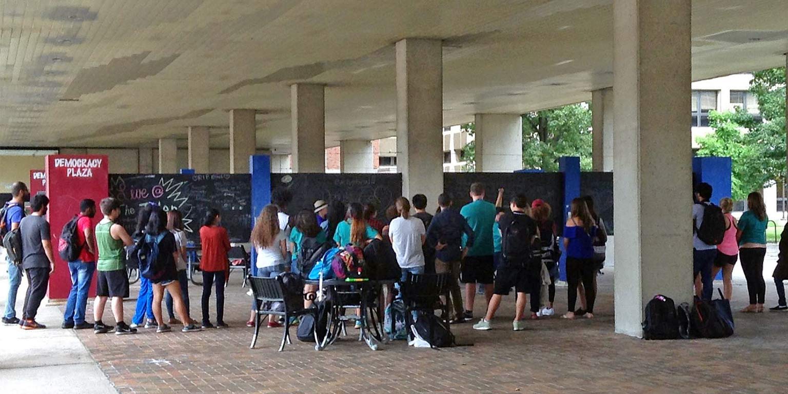 A group of people stands in front of outdoor chalkboards. 